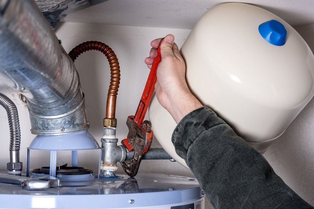 A Person Is Fixing A Water Heater With A Wrench — Richardson Plumbing & Gas Service In Port Macquarie, NSW