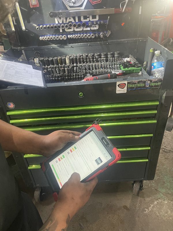 Person using a tablet in front of a green and black tool chest with tools.