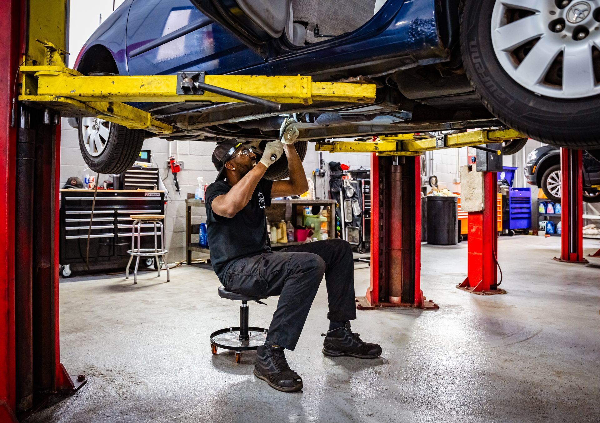 Technician inspecting the undercarriage of a  car at Paul Campanella’s Auto Centers.