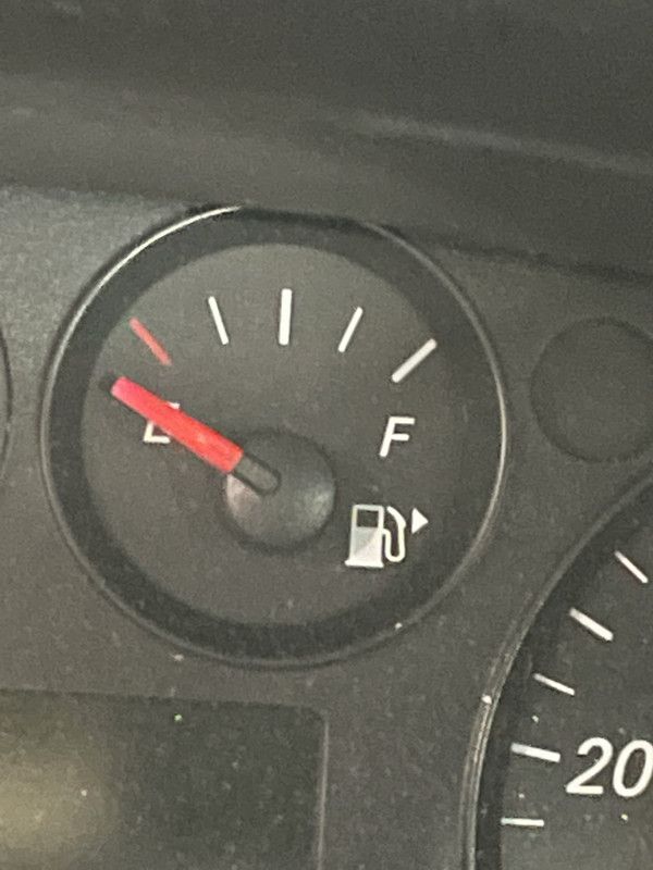 Fuel gauge showing a low fuel level; red needle points near empty.