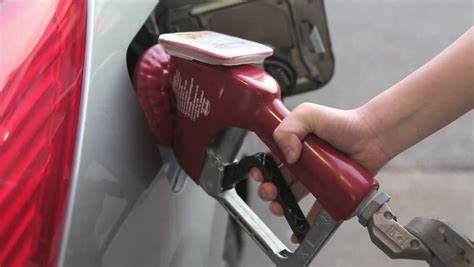 Hand pumping gasoline into a car at a gas station.