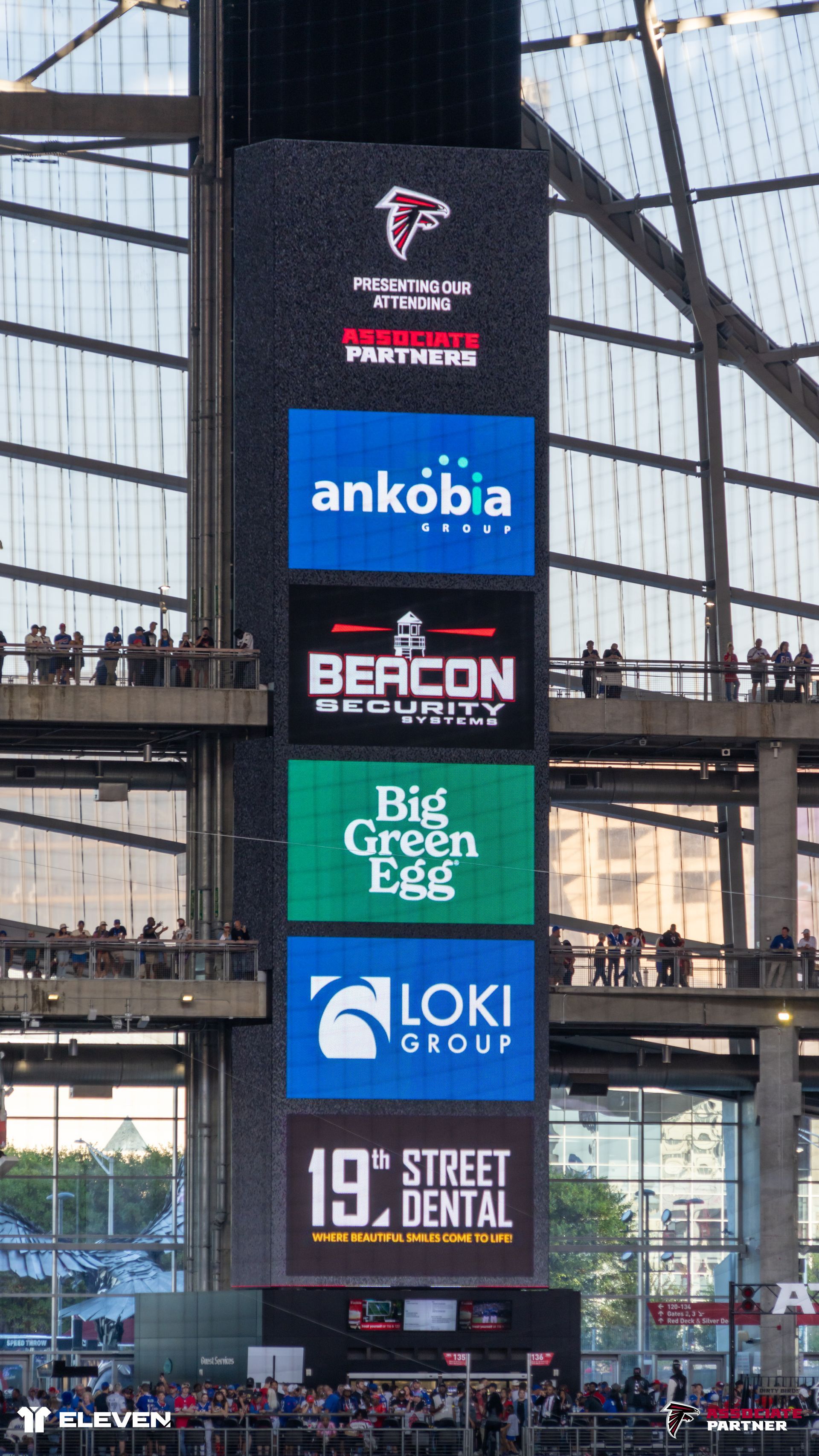 Tall indoor sign tower with stacked sponsor logos inside a stadium entrance.
