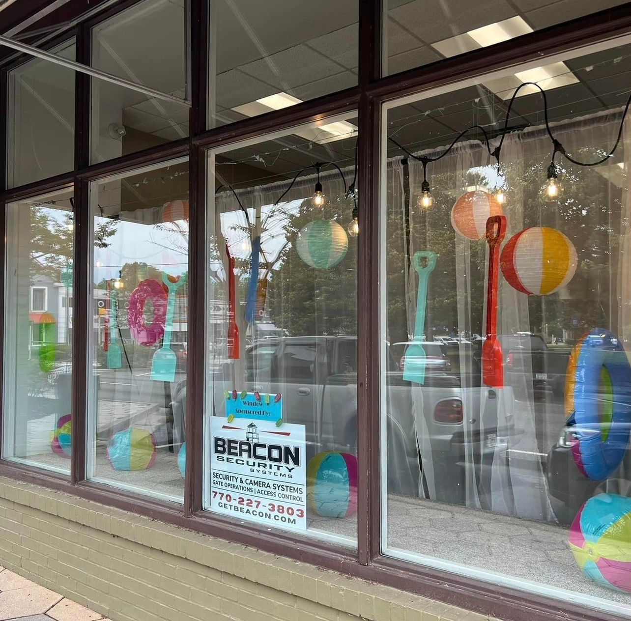 Storefront window display with colorful glass art and a BECON sign.