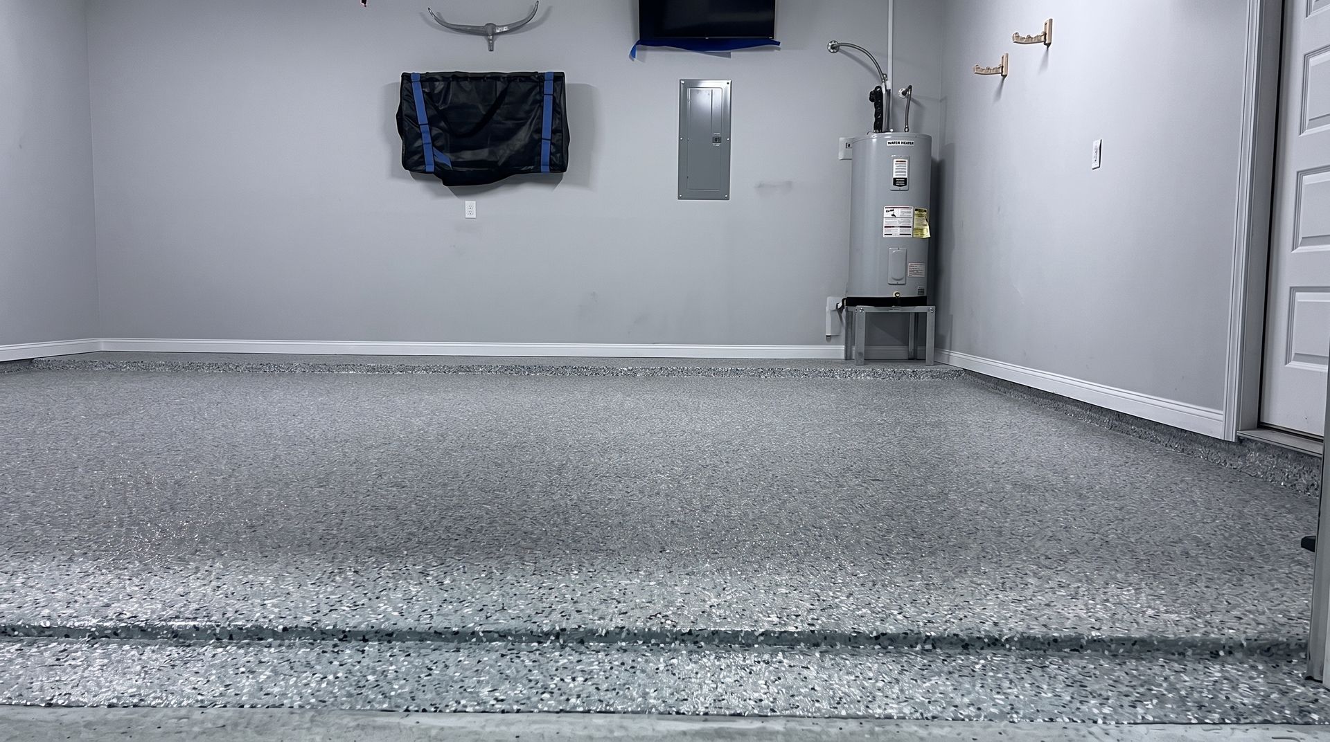 Empty garage with polished concrete floor and a white wall, lit by overhead lights.