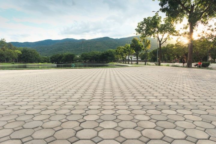 Empty hexagonal-tiled plaza with trees, mountains, and soft sunset light in the background