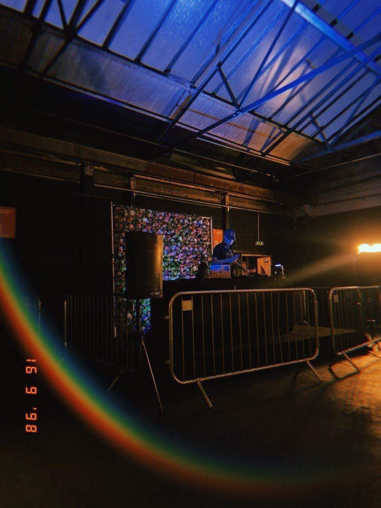 DJ in a dark club, behind a barrier. Rainbow lens flare, blue and orange lighting, September 19, 1998.