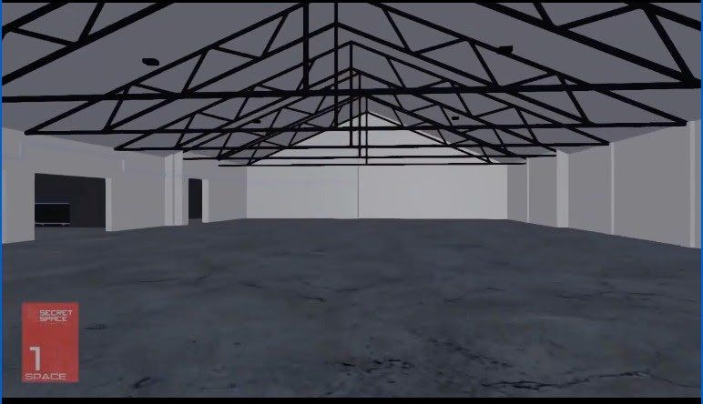 Empty warehouse interior with metal trusses on the ceiling. Gray walls and floor. A door is visible.