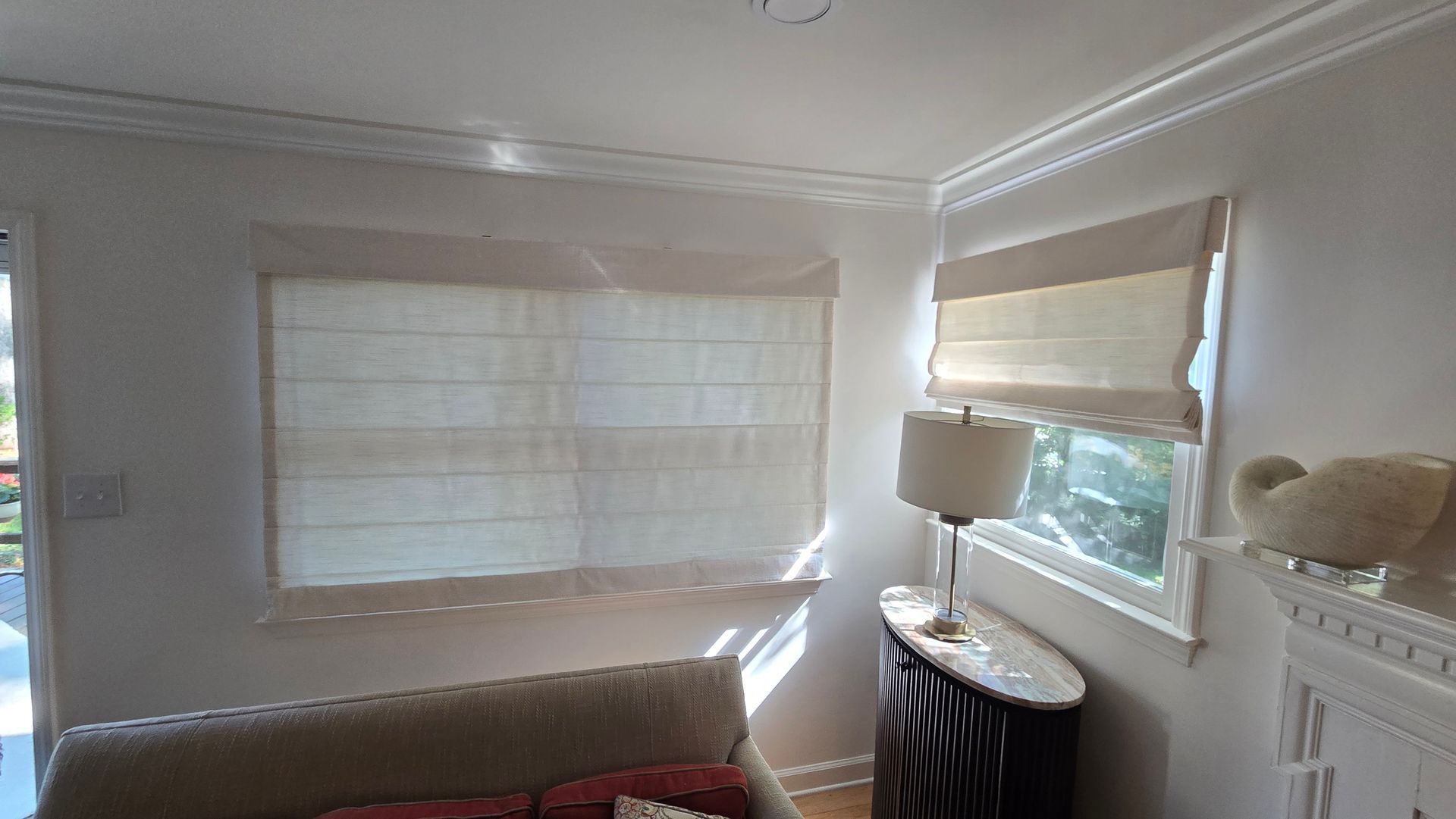 Bright living room with two windows, sheer blinds, a lamp, and a fireplace mantel