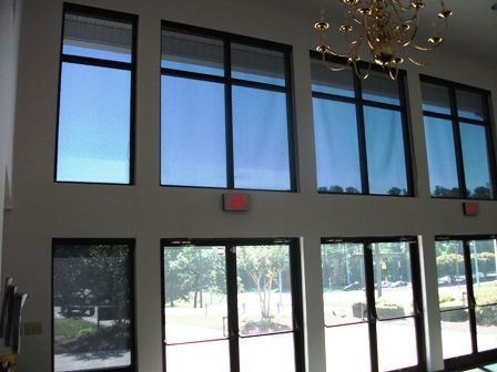 Bright interior with large windows and glass doors, showing trees outside and a chandelier overhead.