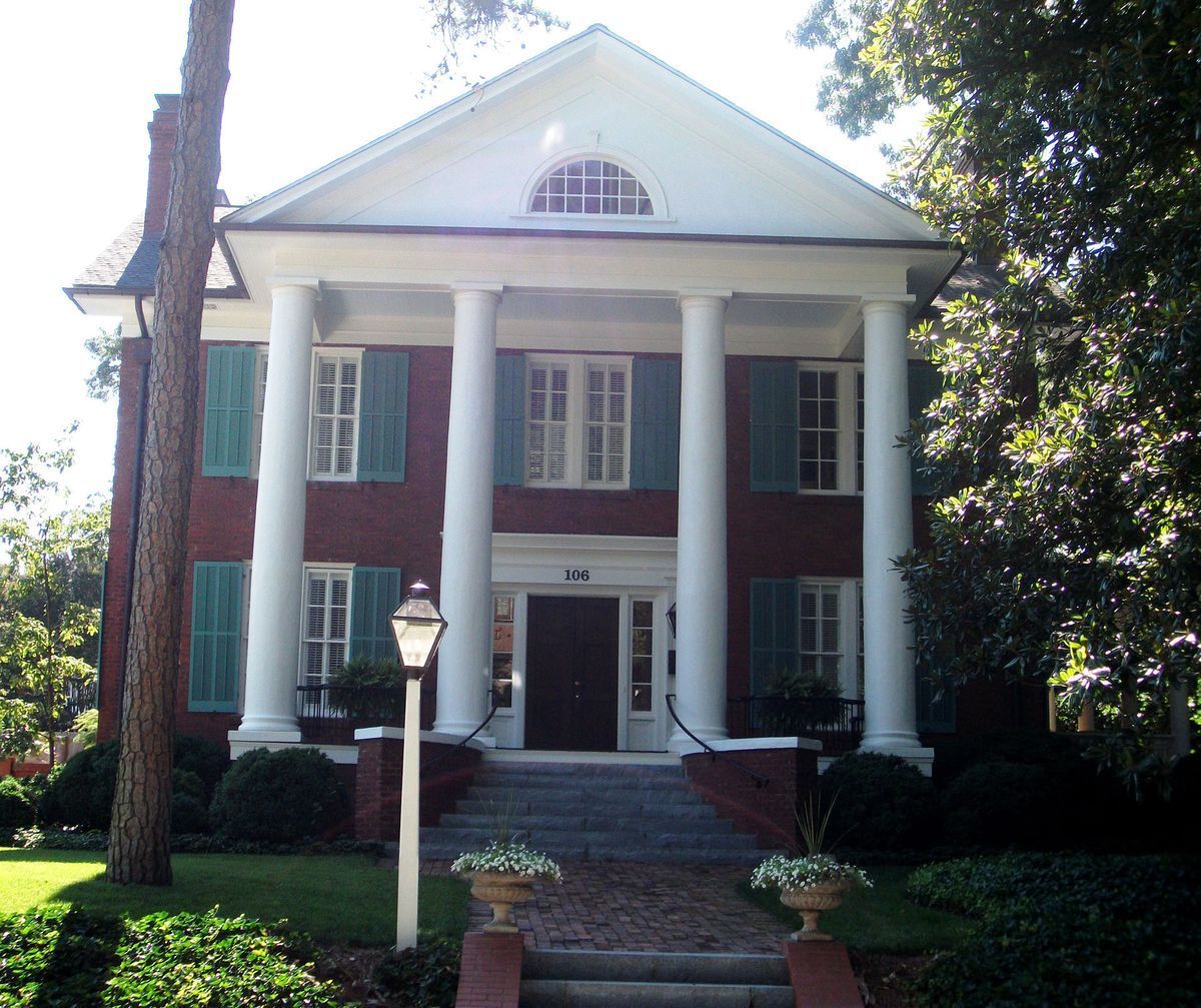 Brick colonial-style house with white columns, red brick facade, and a central front entrance
