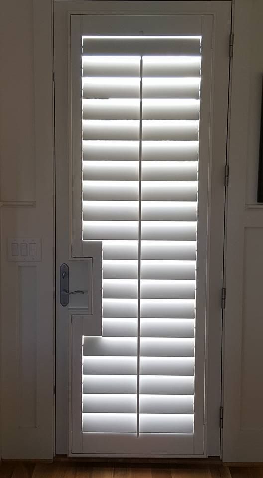 White plantation-style door with closed horizontal blinds letting in light through the slats.