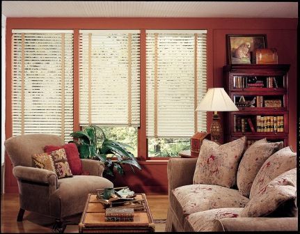 Cozy living room with floral sofa, armchair, coffee table, lamp, and window blinds