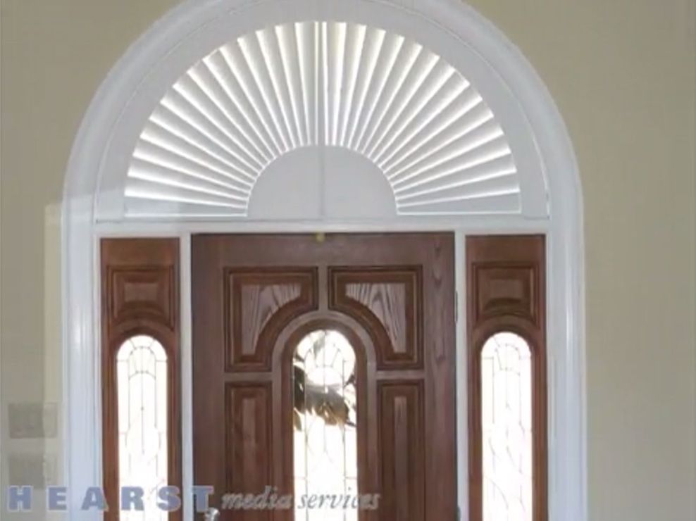 White fanlight above a dark wood front door with sidelights and an arched glass transom