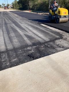 A man is using a shovel to spread asphalt on the ground.