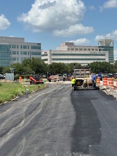A man is using a machine to spread asphalt on the ground.