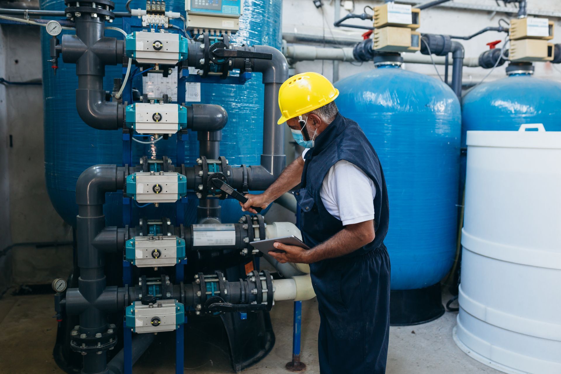 Technician from a water softener company checking chemical water treatment equipment at a facility. Technician from a water softener company checking chemical water treatment equipment at a facility.