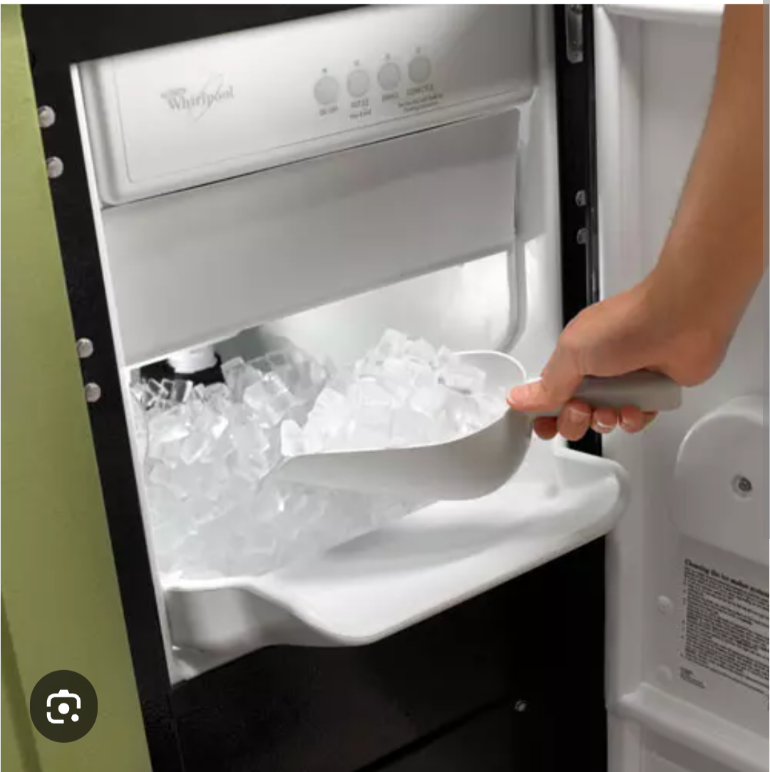 Worker in green shirt and gloves opens an ice machine, revealing a bin full of ice.