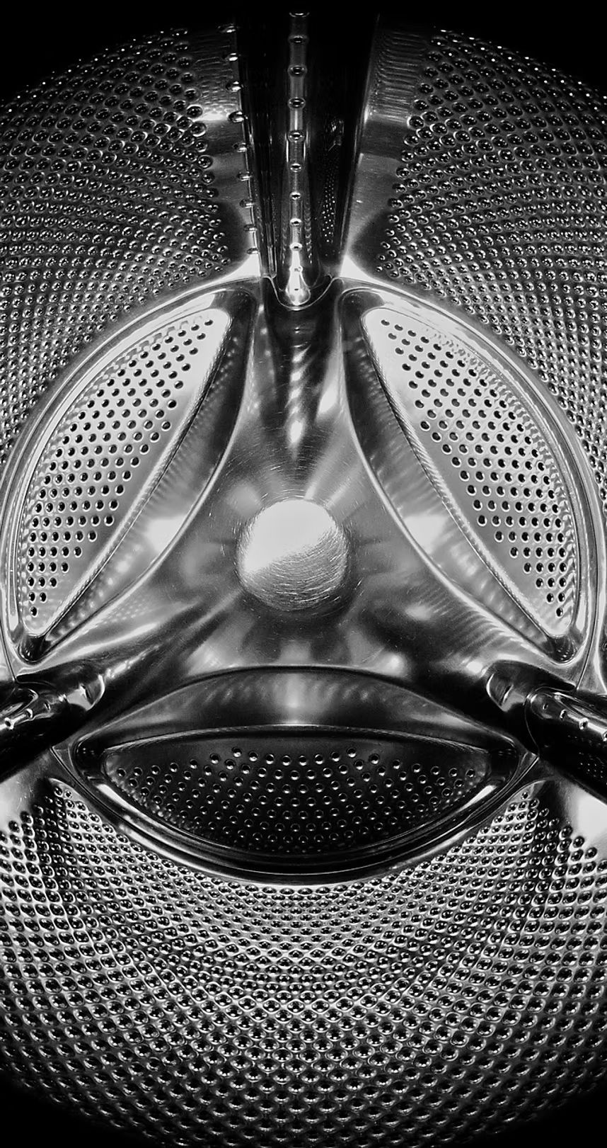 Close-up of a metallic mesh and perforated speaker grille with a central knob-like detail