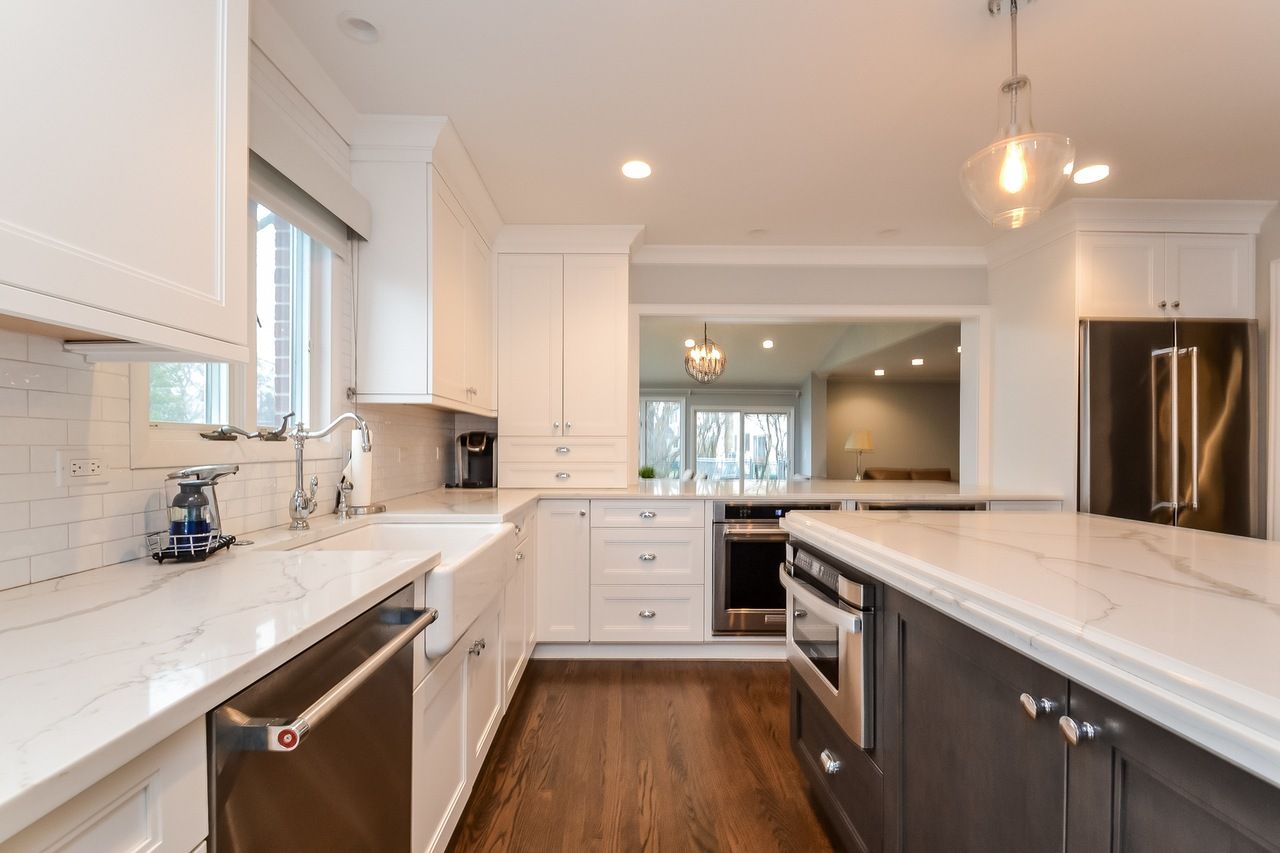 A kitchen with white cabinets and marble counter tops