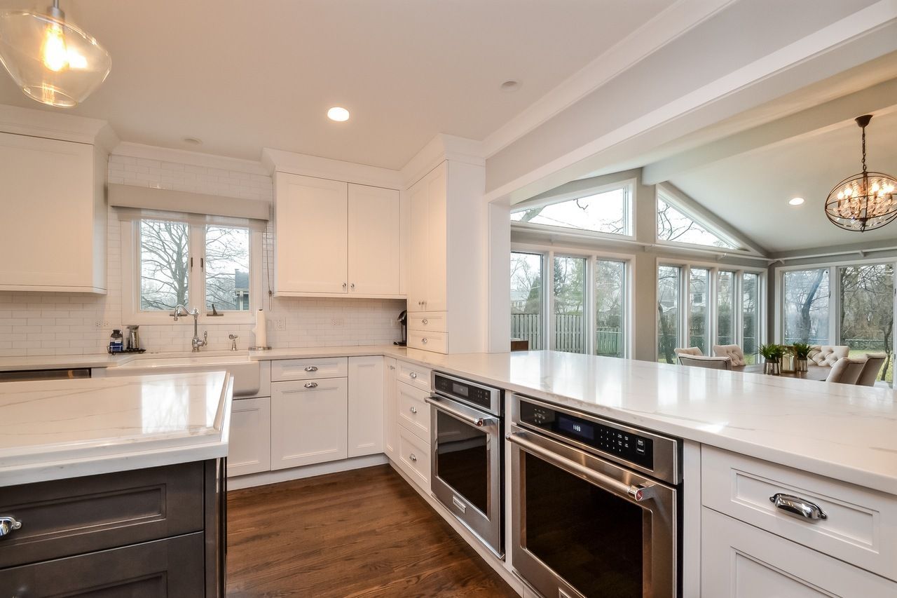 A kitchen with white cabinets , stainless steel appliances , and hardwood floors.