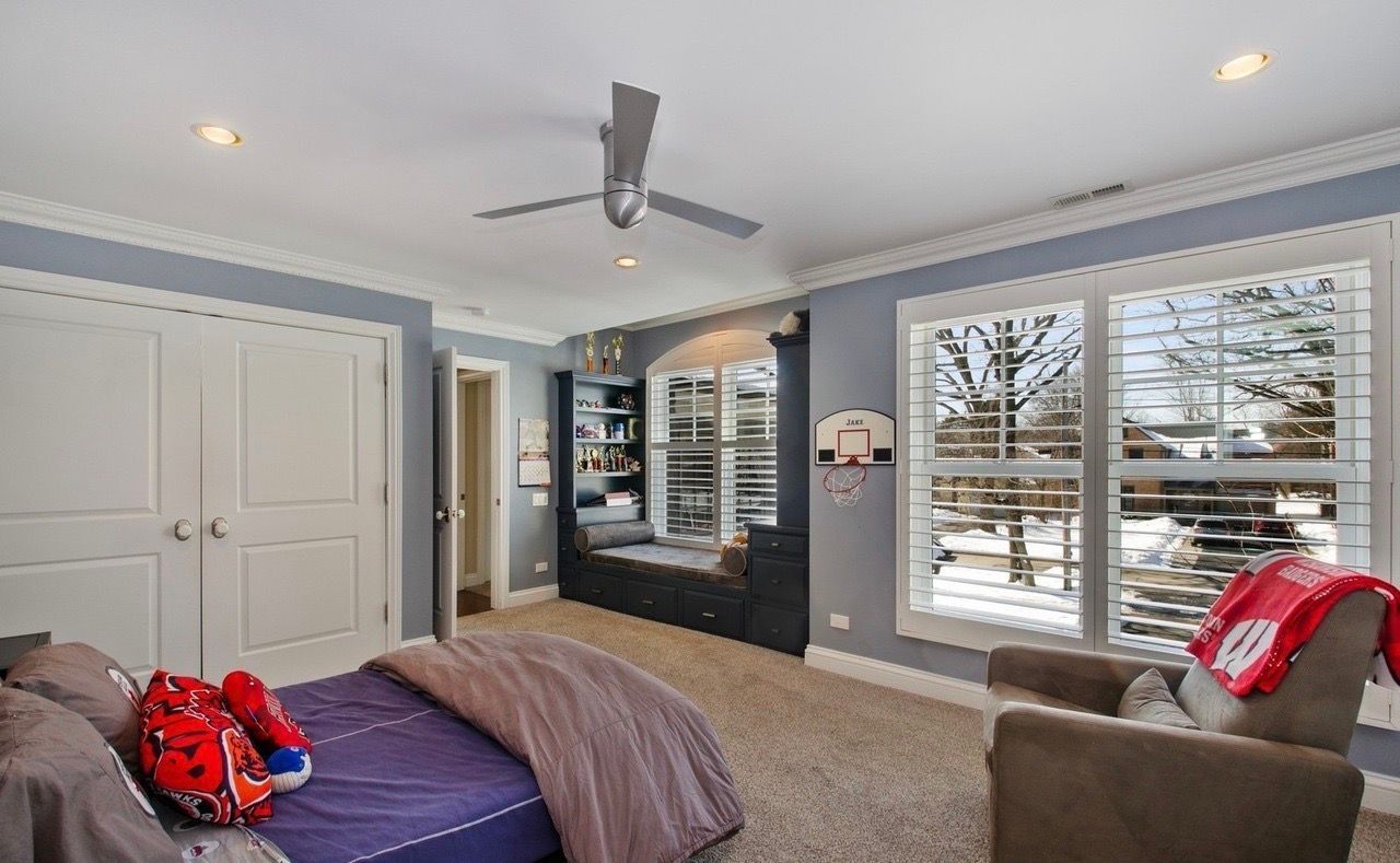 A bedroom with a bed , chairs , and a ceiling fan.