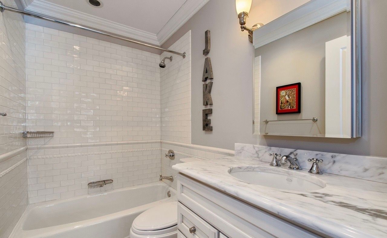 A bathroom with a tub , toilet , sink and mirror.