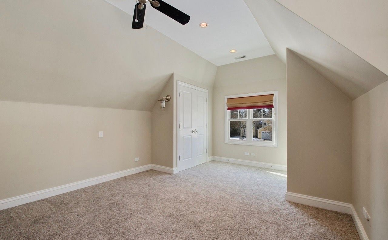An empty bedroom with a ceiling fan and a window.