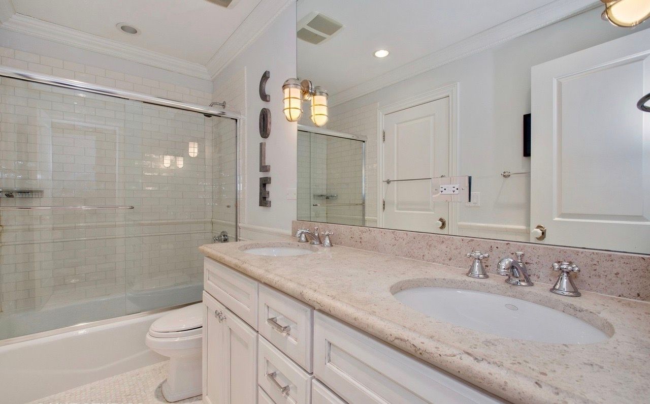 A bathroom with two sinks , a toilet , and a shower.