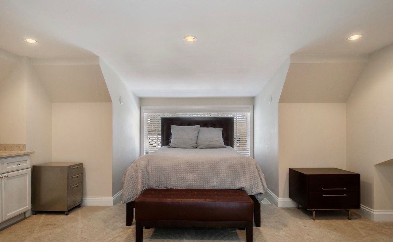 A bedroom with a bed and a bench in it.