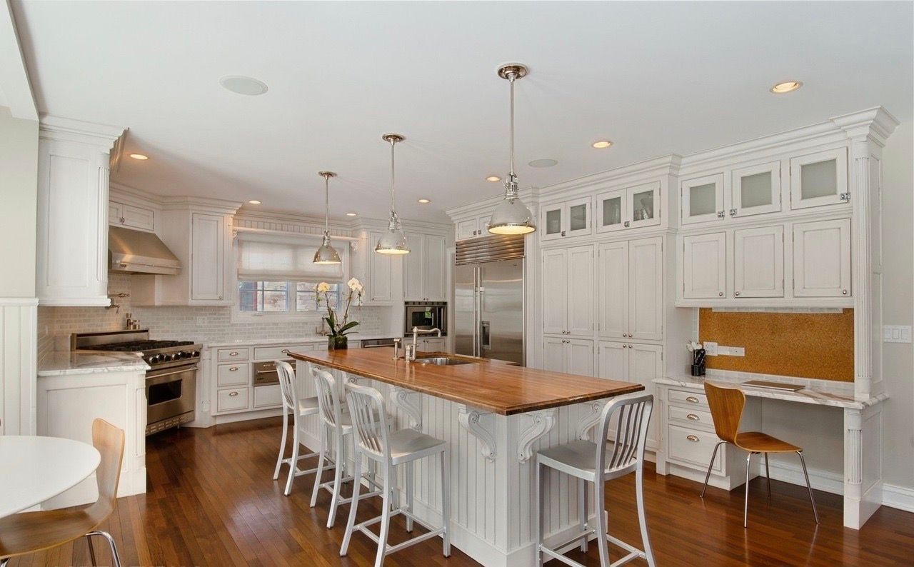A kitchen with white cabinets and a large island in the middle.