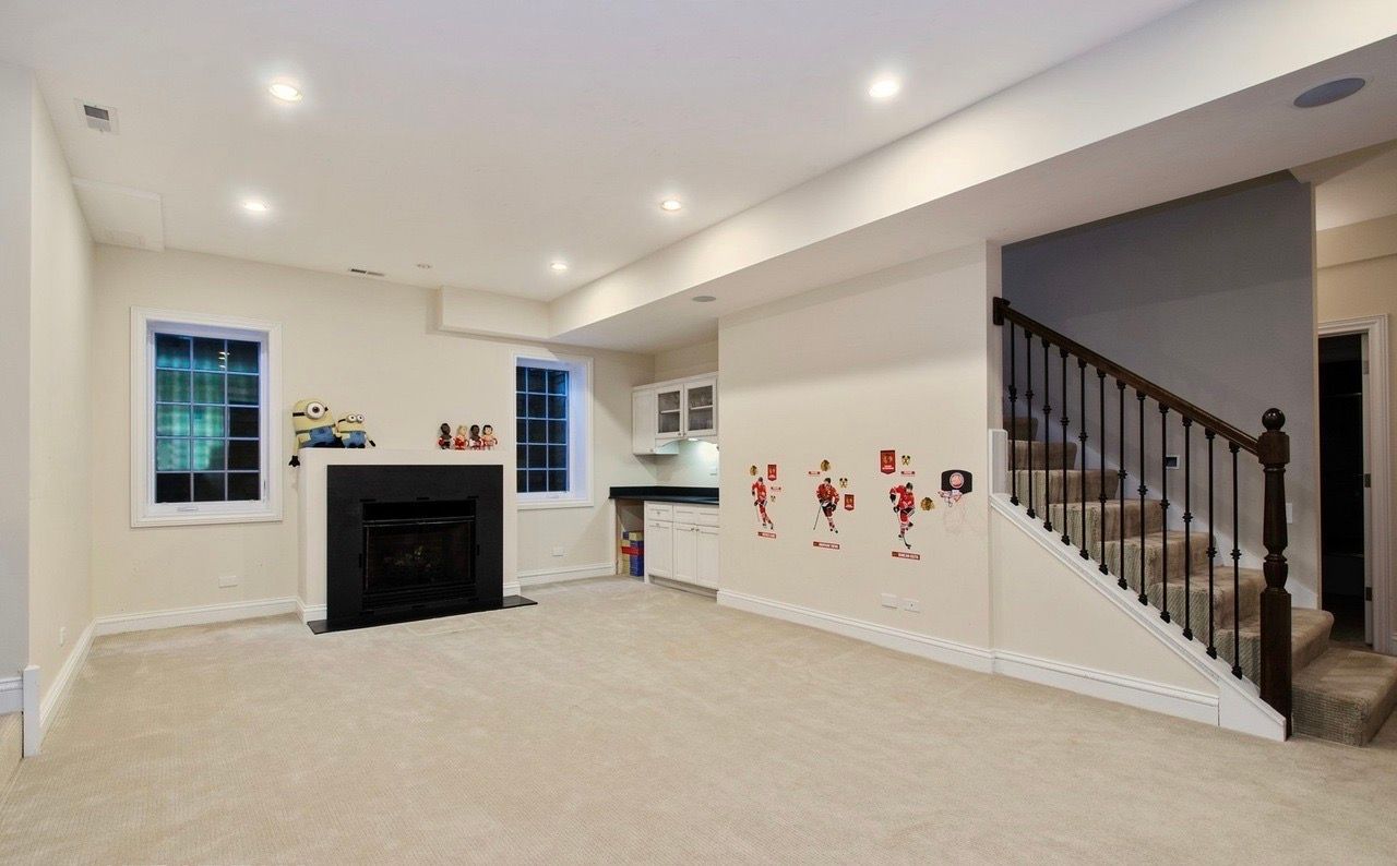 An empty basement with a fireplace and stairs.