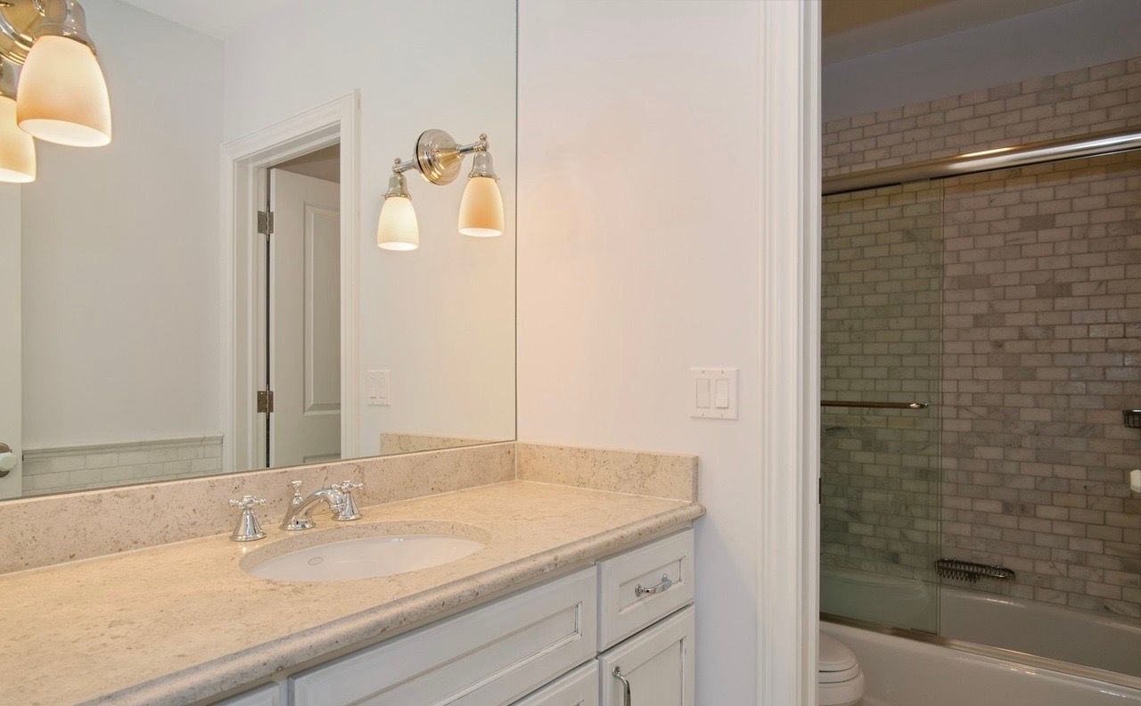 A bathroom with a sink , mirror and bathtub.