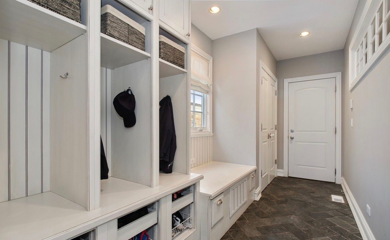 A hallway with lots of storage space and a bench.