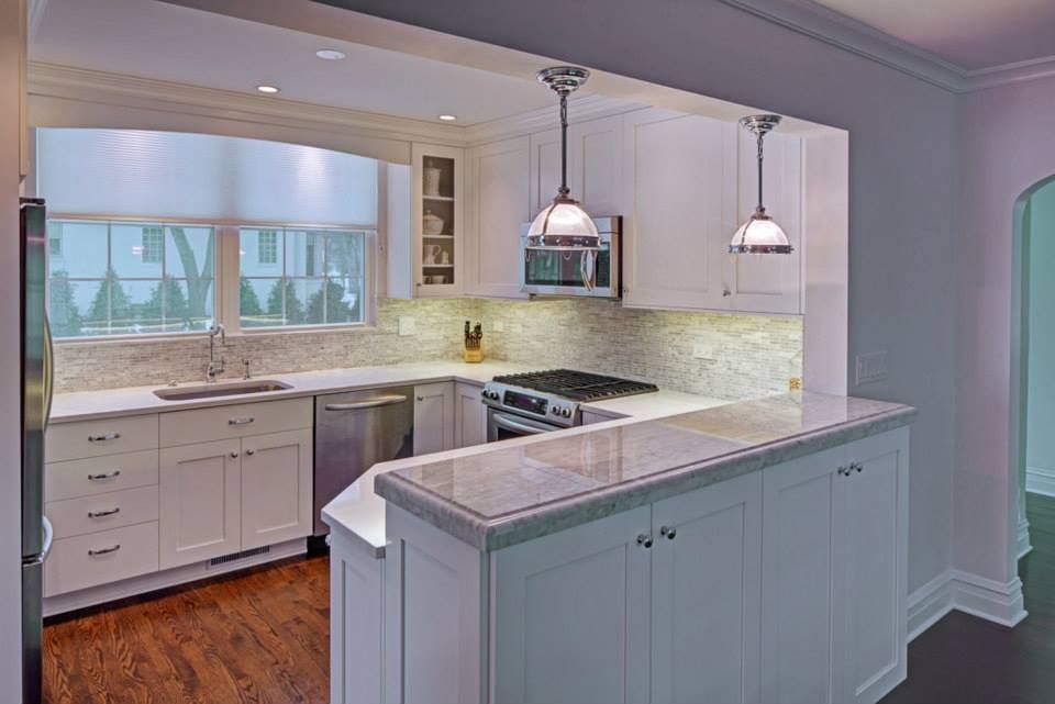 A kitchen with white cabinets , a stove , a sink , and a microwave.