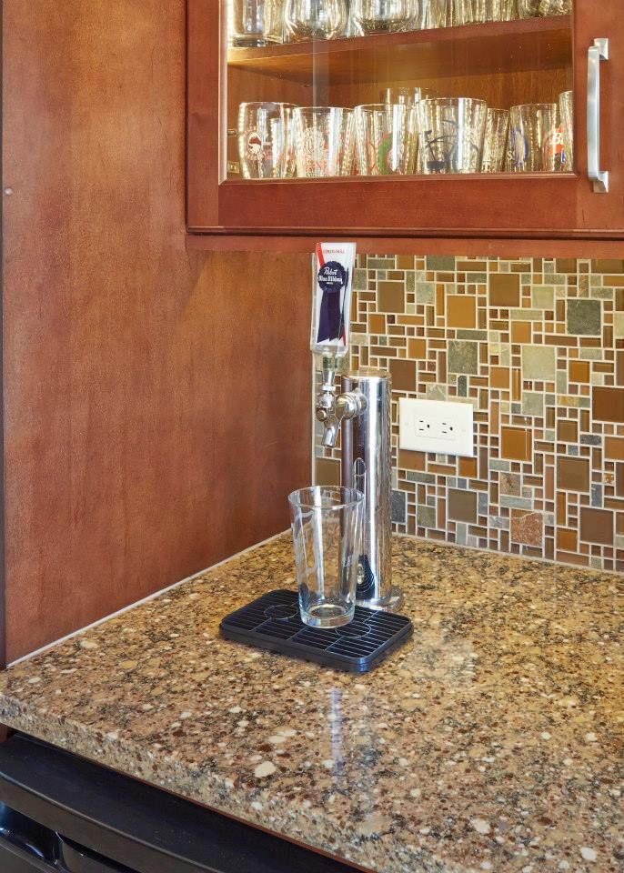 A glass sitting on a counter next to a glass dispenser