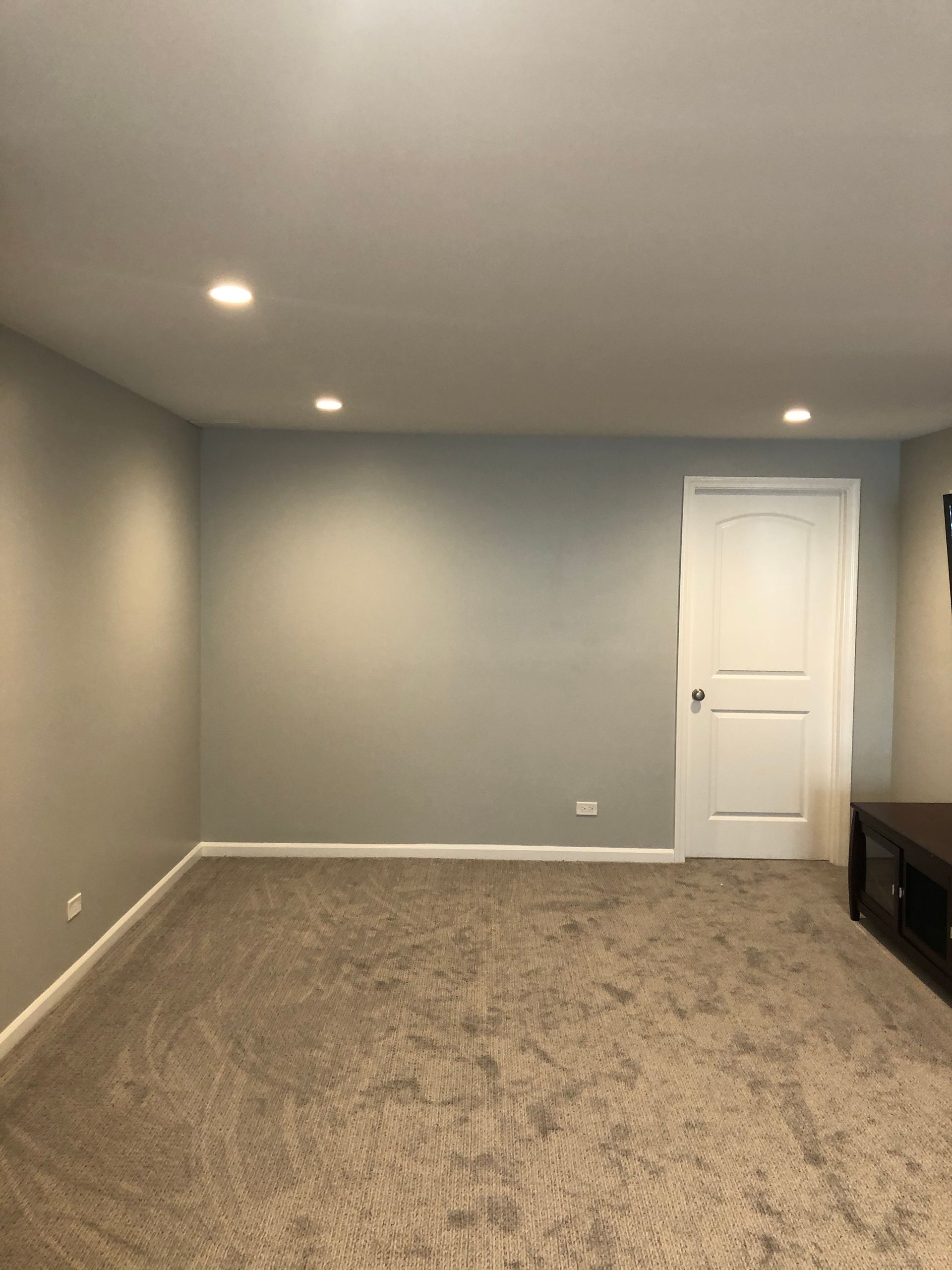 An empty basement with a carpeted floor and gray walls.