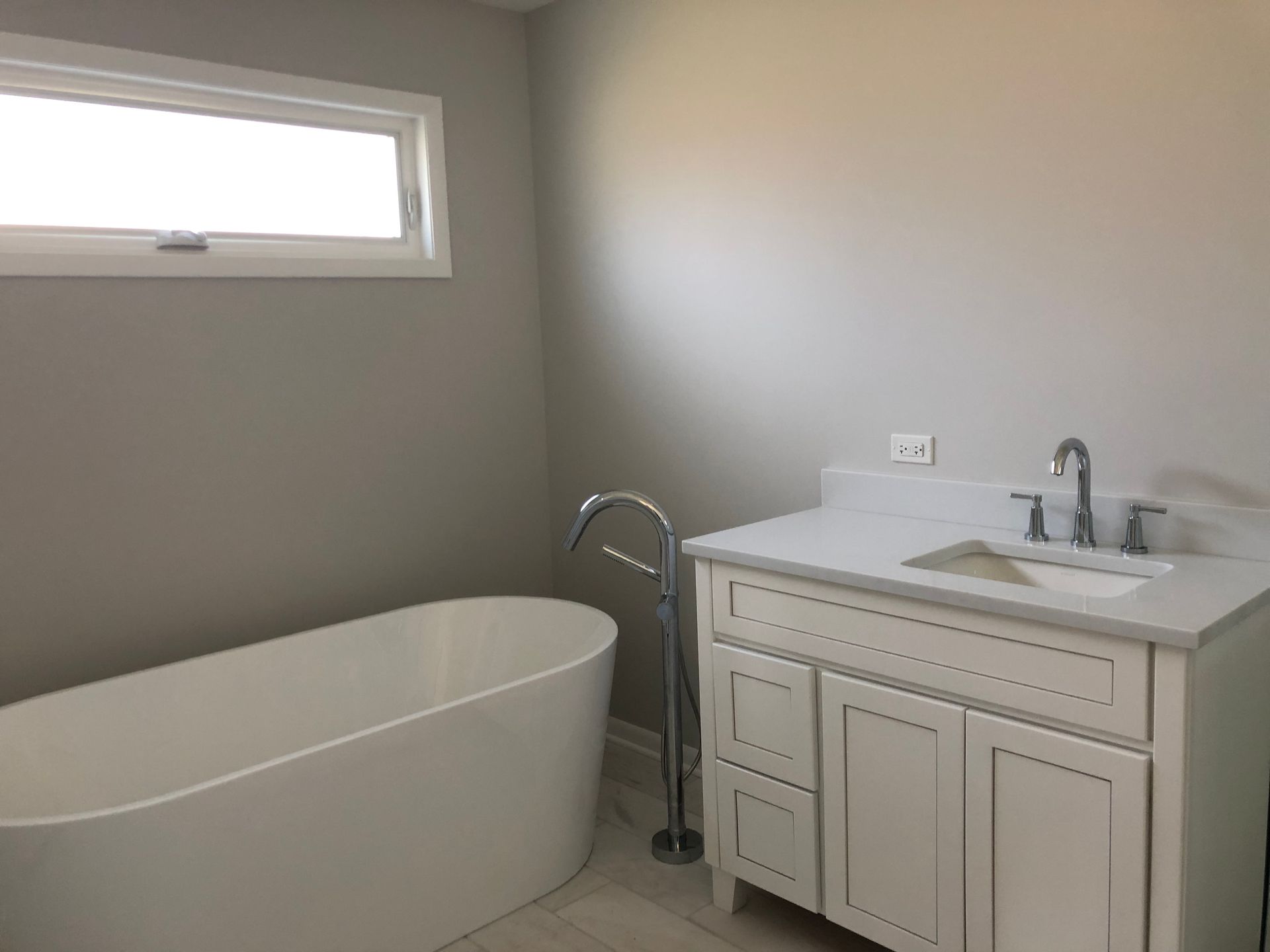 A bathroom with a tub , sink , and window.