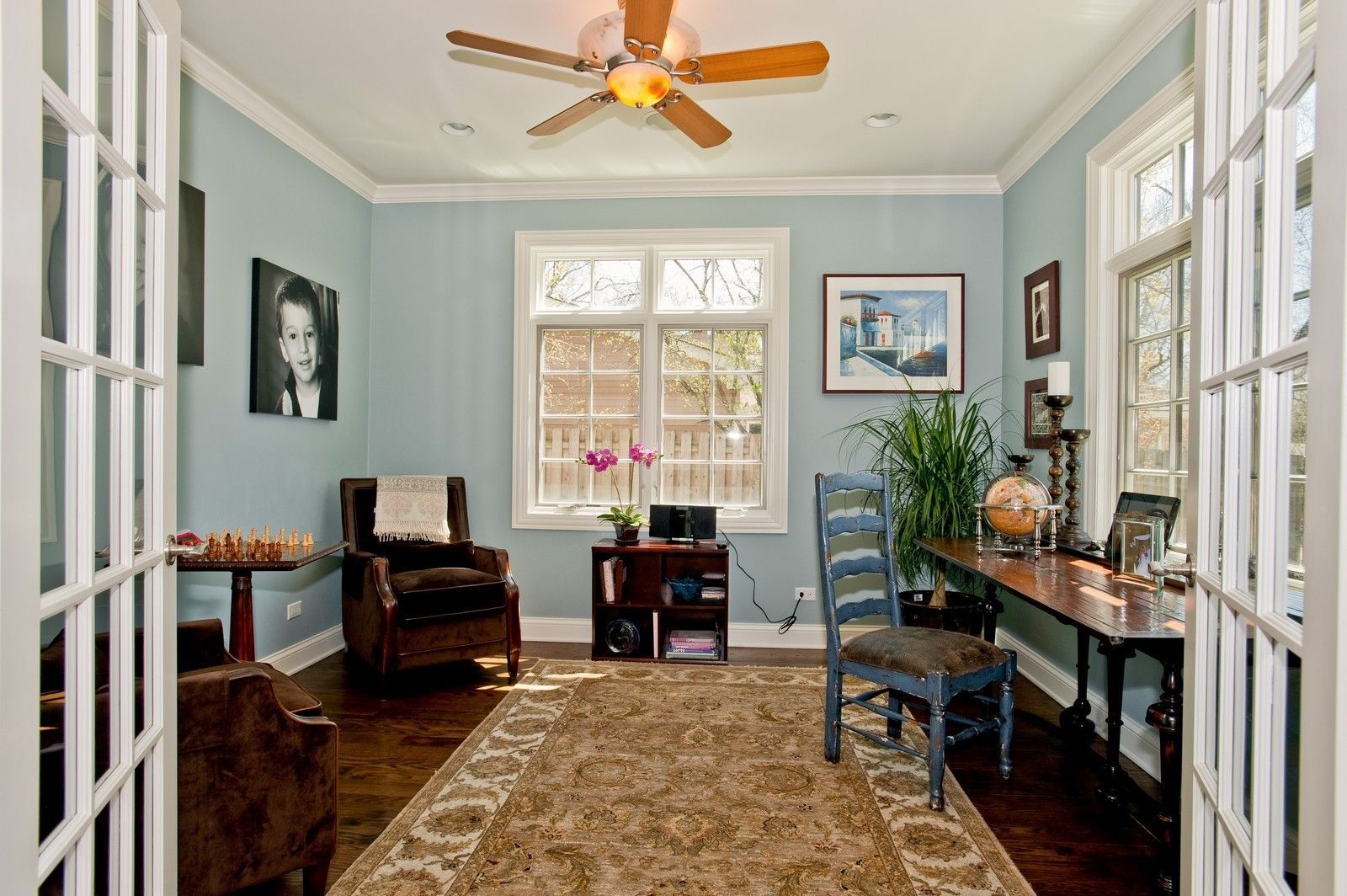 A living room with blue walls and a ceiling fan.