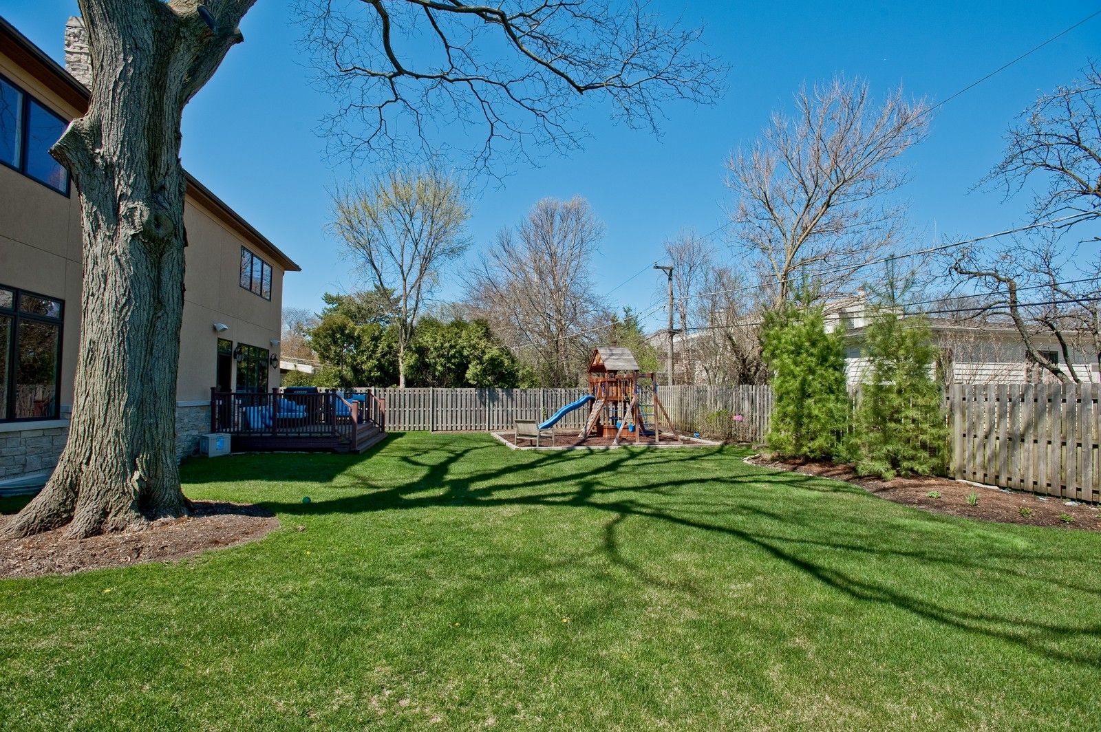 A large lawn with a playground in the backyard of a house.