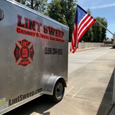 A trailer with an american flag on it is parked on the side of the road.