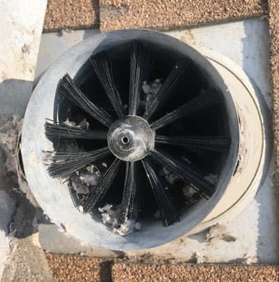 A close up of a brush in a hole in a brick wall.