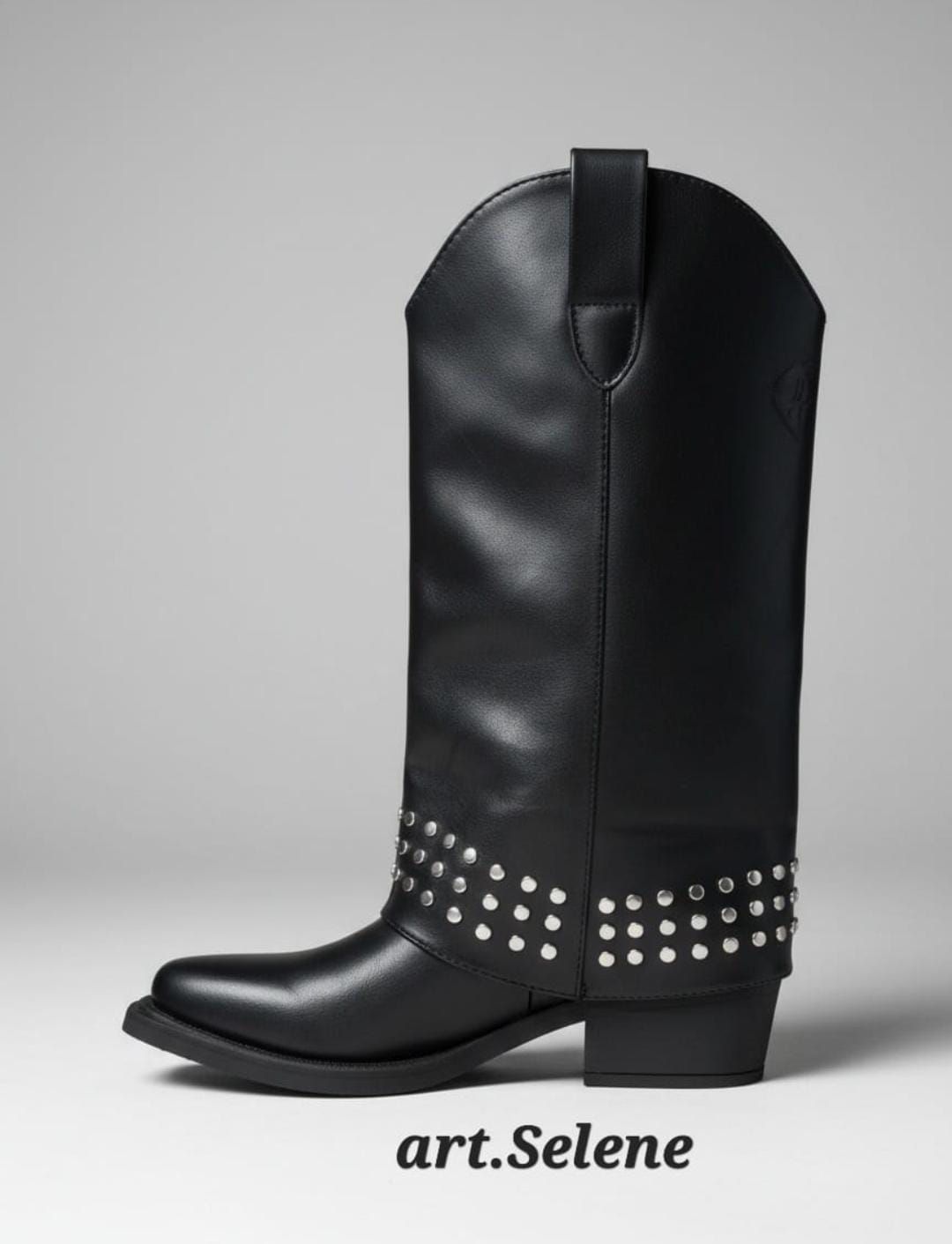 Bota vaquera negra con tachuelas plateadas y punta afilada sobre fondo gris.