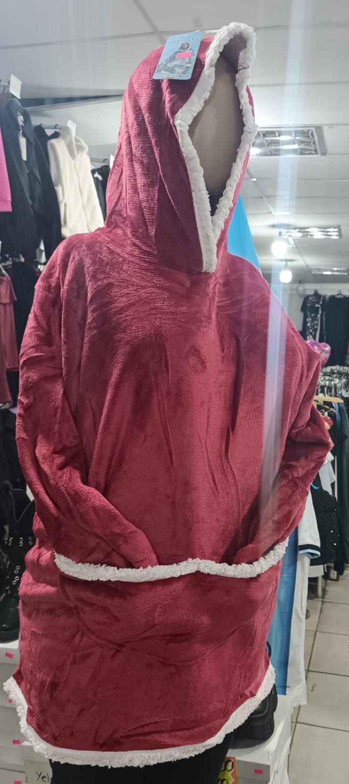 Abrigo de invierno rojo con capucha y ribete de piel blanca, expuesto en un maniquí en el interior de una tienda.