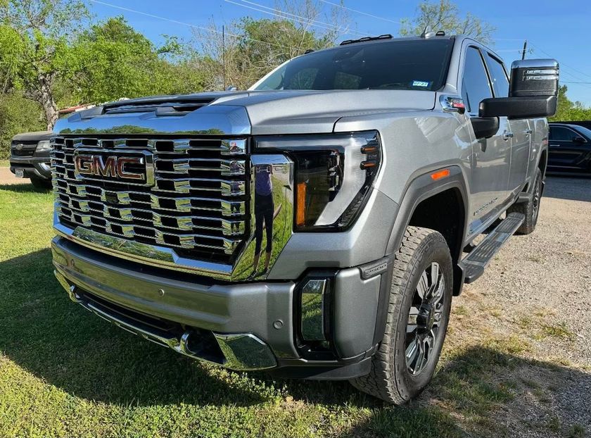 Silver GMC pickup truck parked on grass under a blue sky