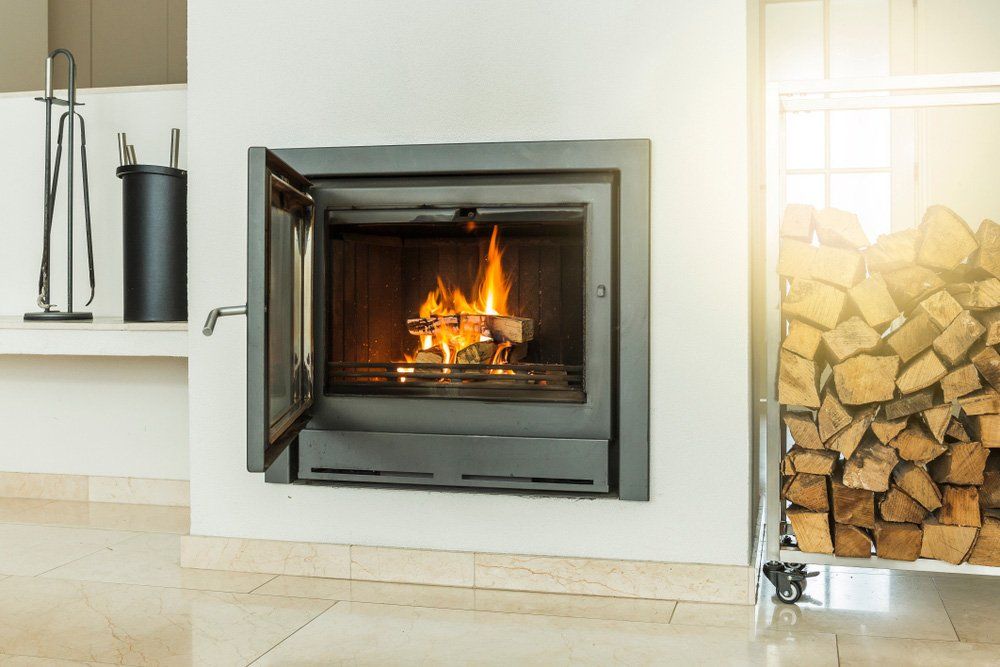 A Fireplace With the Door Open and a Pile of Wood in the Background — Greg Mitchell Plumbing In Murgon, QLD