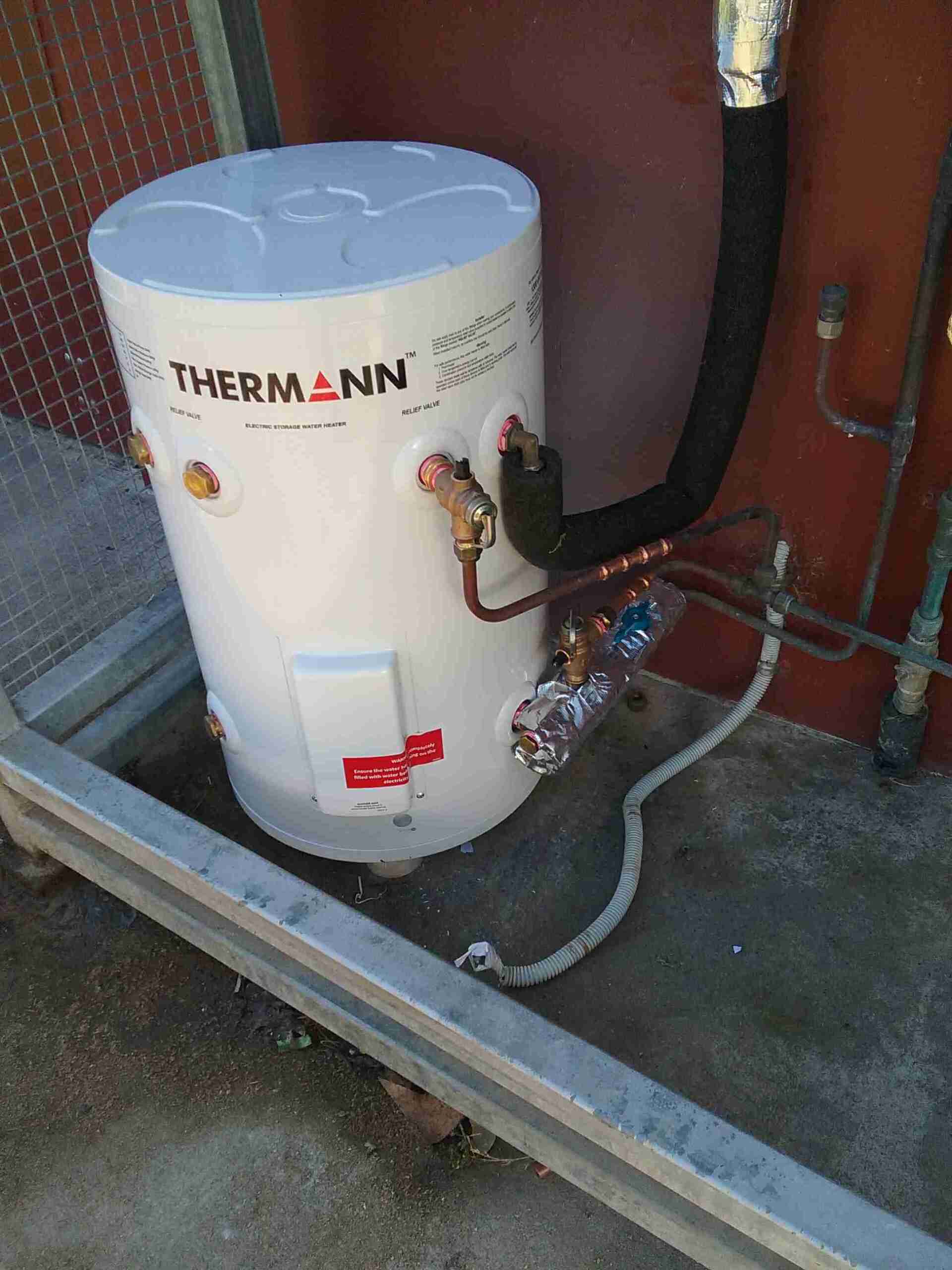 A White Water Heater is Sitting on the Side of a Building — Greg Mitchell Plumbing In Murgon, QLD