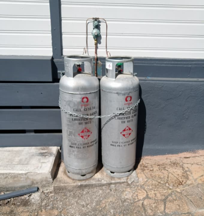 Two Propane Tanks Are Chained to the Side of a Building — Greg Mitchell Plumbing In Murgon, QLD
