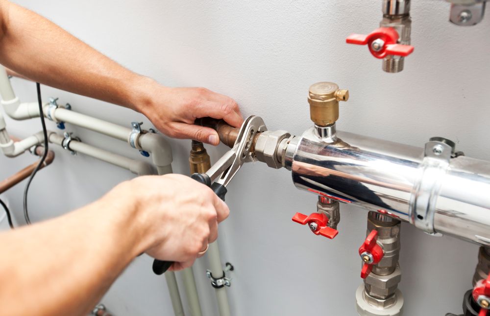A Person is Fixing a Pipe With a Wrench — Clinton McArthur Plumbing in Maroochydore, QLD