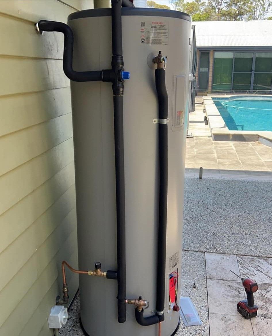 A Large Water Heater is Sitting on the Side of a House Next to a Pool — Clinton McArthur Plumbing in Landsborough, QLD