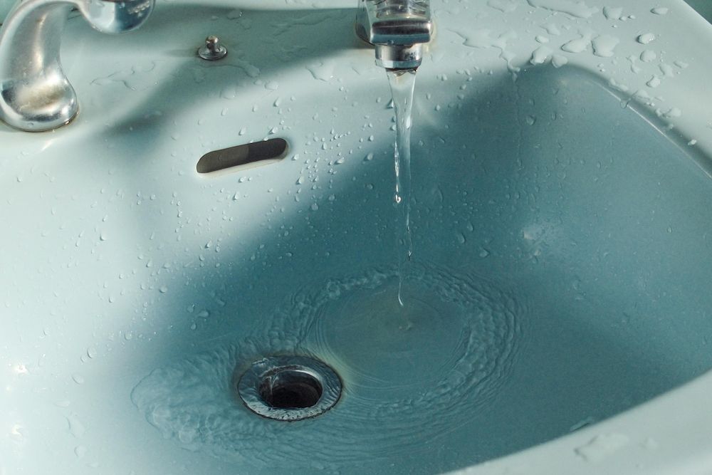 A Close Up of a Bathroom Sink With Water Running From the Faucet — Clinton McArthur Plumbing in Landsborough, QLD